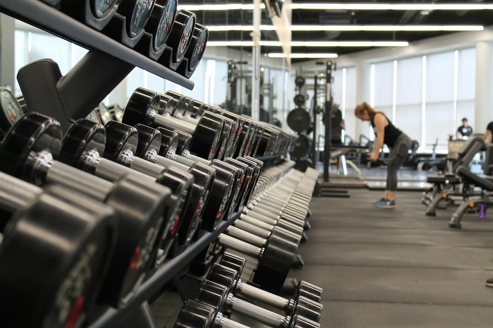 A bright, modern fitness facility with organized gym equipment including dumbbells and machines