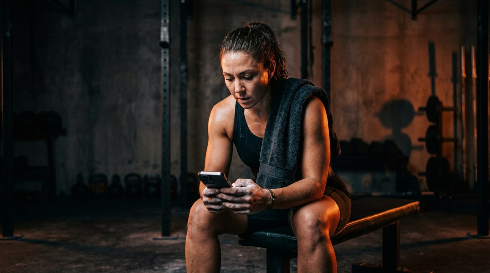 A man on a workout bench reading coaching advice on his phone